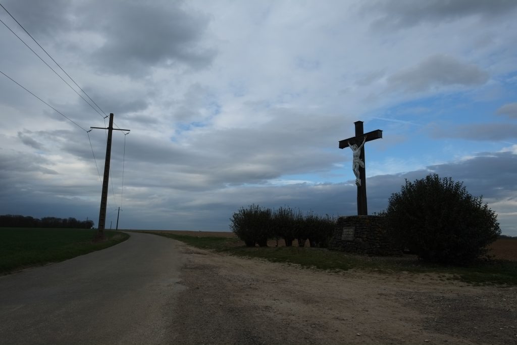 Mimétisme sur le bord d'une route entre un crucifix et un pylône.