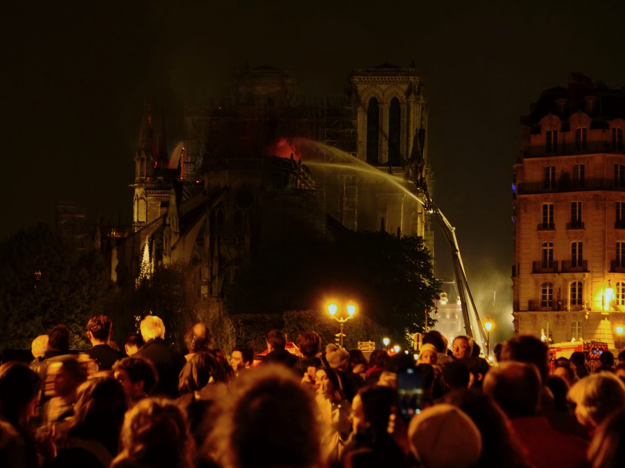 Une foule de parisiens regardant Notre Dame brûler dans la nuit du 15 au 16 avril