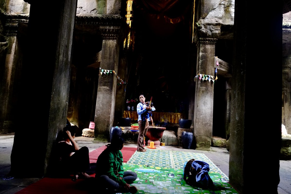Une garde des temples d'Angkor et quelques locaux priant à un petit temple improvisé