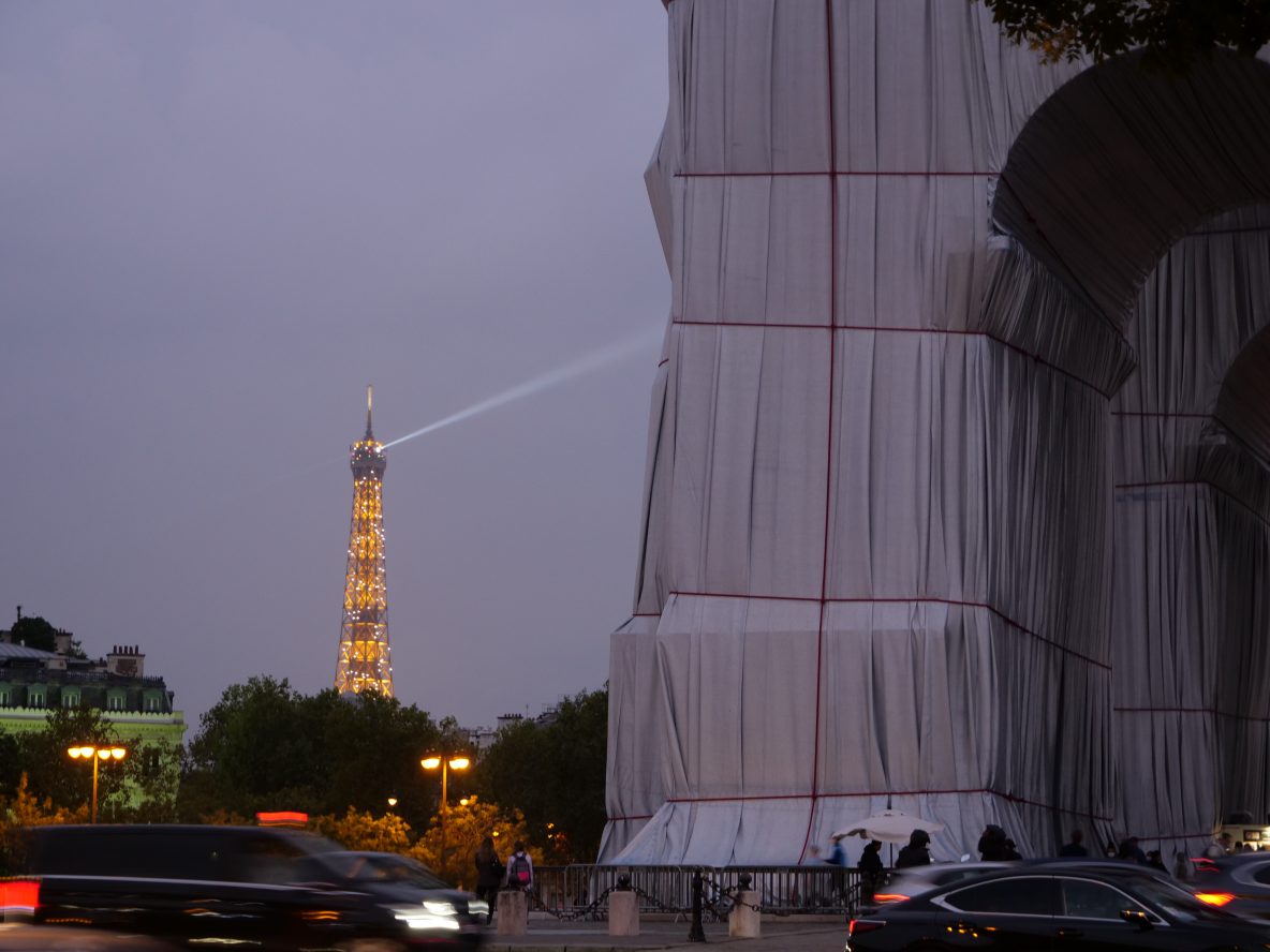 L'arc de Triomphe emballé et la tour Eiffel à la tombée de la nuit