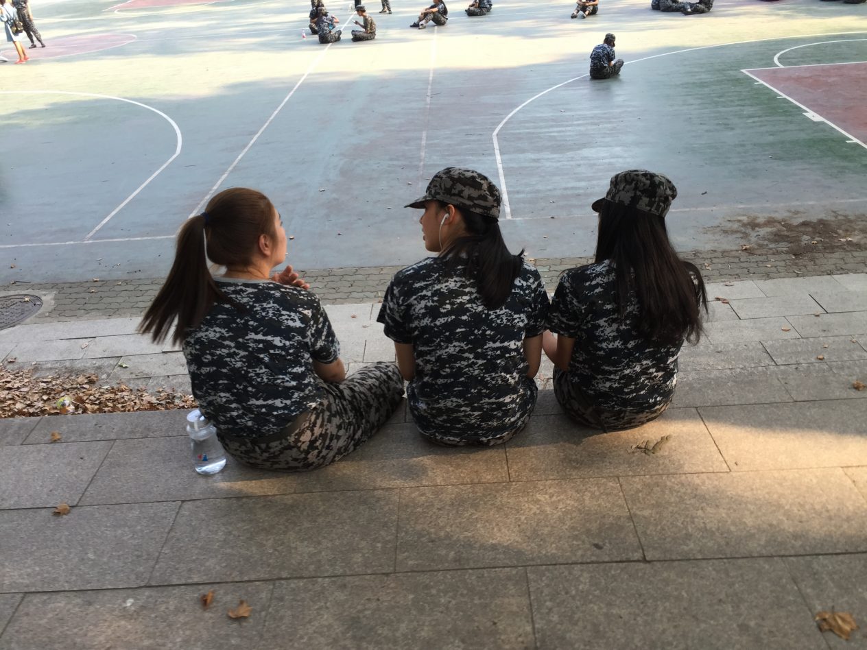 Trois étudiantes de l'université de Wuhan assises au bord d'un terrain