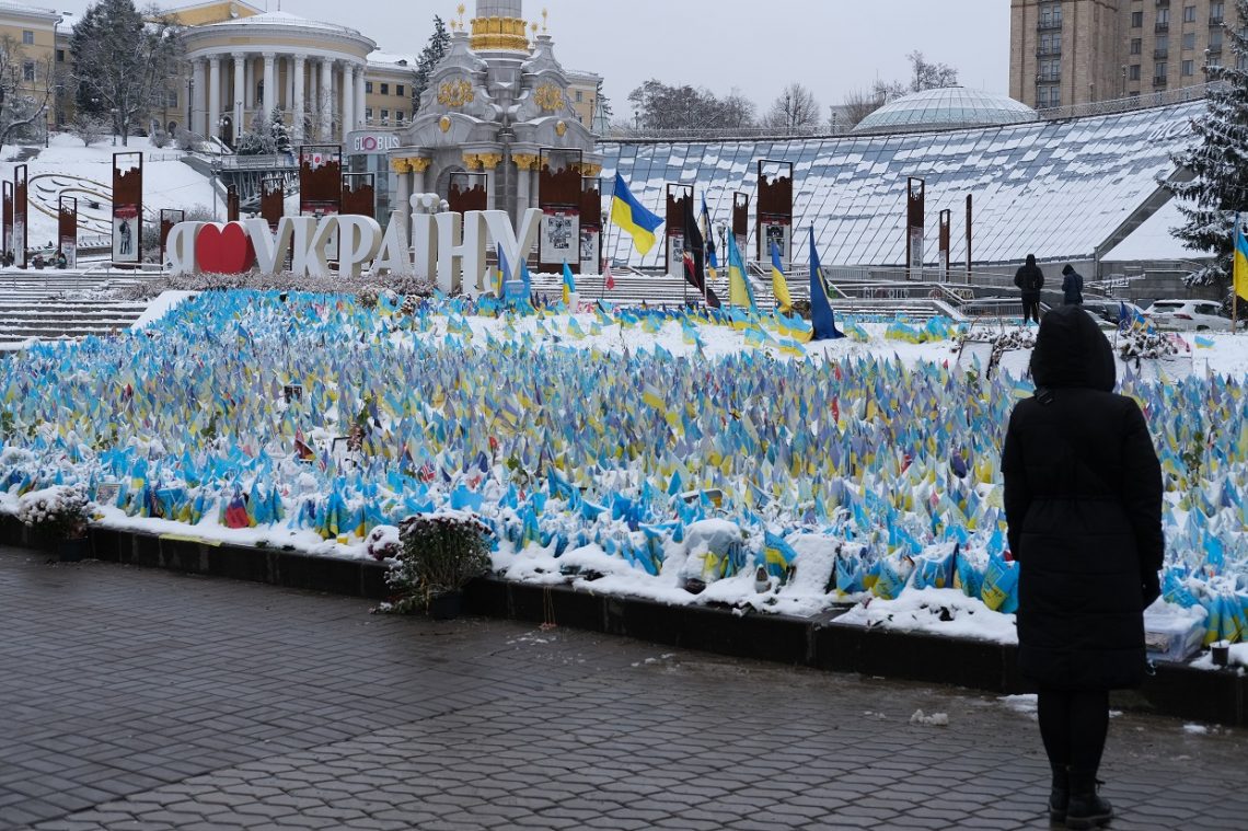 Une femme se recueille devant les petits drapeaux de la place Maidan