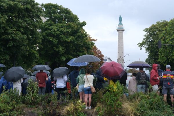 Des parisiens et des touristes sous la pluie qui regardent passer des cyclistes - le 27 juillet 2024